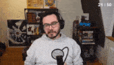 a man wearing headphones and glasses is sitting in front of a microphone with the number 21/50 visible in the corner