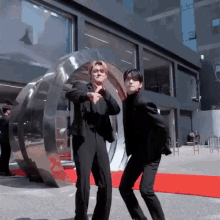 two men in suits are dancing on a red carpet