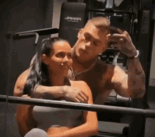 a man is taking a picture of himself and his girlfriend in a gym .