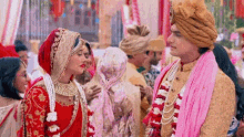 a bride and groom are standing next to each other in a crowd of people .