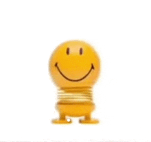 a yellow spring toy with a smiley face on it is standing on a white surface .