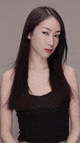 a woman wearing a black tank top and red lipstick looks at the camera