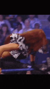a woman is laying on her back in a wrestling ring with a crowd behind her
