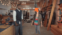 a man and a woman are standing in a clothing store with an orange arrow pointing to the woman 's head