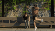 a man is jumping in the air while a woman sits on a bench behind him