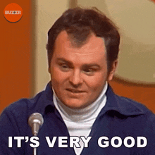 a man standing in front of a microphone with the words it 's very good above him