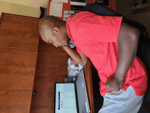 a man in a red shirt sits at a desk in front of a laptop with a screen that says linkedin