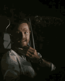 a man in a white shirt and tie sits in a dark car