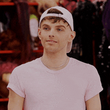 a young man wearing a pink shirt and a white hat