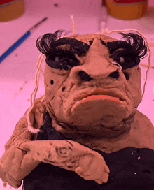 a close up of a clay sculpture of a person with a tattoo on the arm