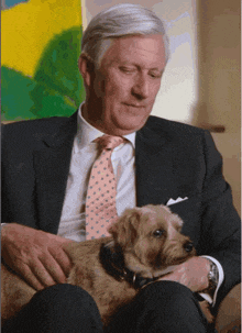 a man in a suit and tie is holding a dog