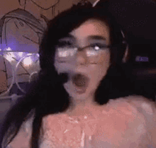 a woman wearing glasses and headphones is making a funny face with her mouth open .