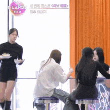 a group of girls sit at a table in front of a sign that says iland