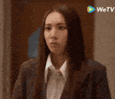 a woman in a suit is standing in front of a wetv advertisement
