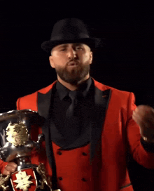 a man with a beard is wearing a black hat and a red jacket