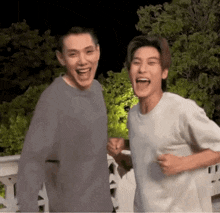 two young men are standing next to each other laughing and having fun .