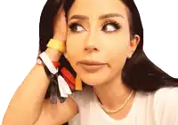 a woman wearing a white t-shirt and a pearl necklace holds her hand to her face