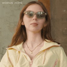 a woman wearing sunglasses and a yellow jacket with the words workin ' moms on the bottom