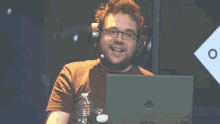 a man wearing headphones and glasses is sitting in front of a laptop computer