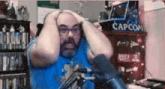 a man holds his head in front of a capcom cabinet