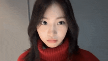 a young woman wearing a red turtleneck sweater is making a face .