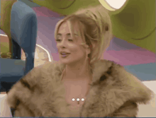 a woman wearing a fur coat is smiling with her eyes closed .