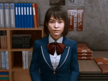 a girl in a school uniform is standing in front of a bookshelf in a library .