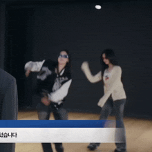 a blurry picture of two women dancing with a blue and white banner in the foreground that says " 있습니다 "