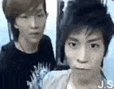 two young men are standing next to each other and one of them is making a face .