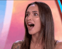 a woman with a tattoo on her arm is making a surprised face with her mouth open .