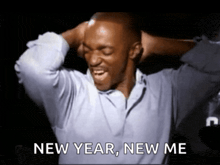 a man in a blue shirt is holding his head and says new year new me
