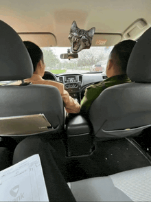 two men are sitting in a car with a cat sticker on the windshield