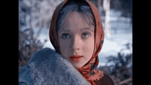 a close up of a young girl wearing a scarf around her head and a fur coat .