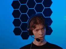 a young man wearing headphones and a microphone looks at the camera