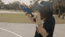 a man wearing a hat with the word bitch on it holds a water gun