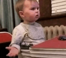 a baby is sitting on a table with a toy car on it .