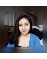 a woman in a blue sweater is smiling in a bedroom