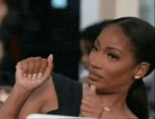 a woman is sitting in a chair with her hand on her chin and giving a thumbs up .