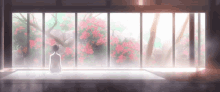 a woman sits in front of a large window with pink flowers in the background ..
