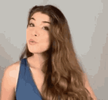 a woman with long brown hair is wearing a blue tank top .