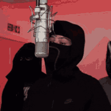 a man wearing a black nike jacket is standing in front of a microphone