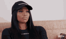 a woman wearing a black balenciaga hat and a black shirt