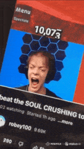 a man wearing headphones is laughing in front of a screen that says 10,073 on it