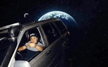 a man is sitting in a car in front of the earth .