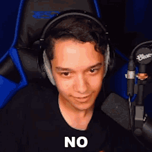 a young man wearing headphones and a black shirt is sitting in front of a microphone and saying no .