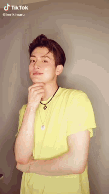 a young man wearing a yellow shirt and a necklace has a tiktok sticker on his face