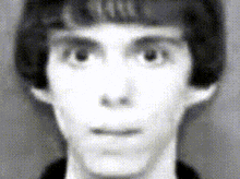 a black and white photo of a young man 's face with a blurred background