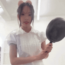 a girl in a white shirt is holding a pan