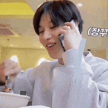 a man is sitting at a table talking on a cell phone while eating a bowl of food .