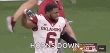 a football player wearing a oklahoma jersey is running on a field .